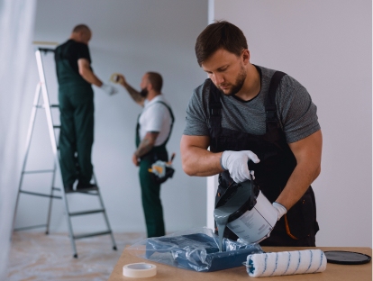 Equipo de renovadores pintando paredes y preparando pintura